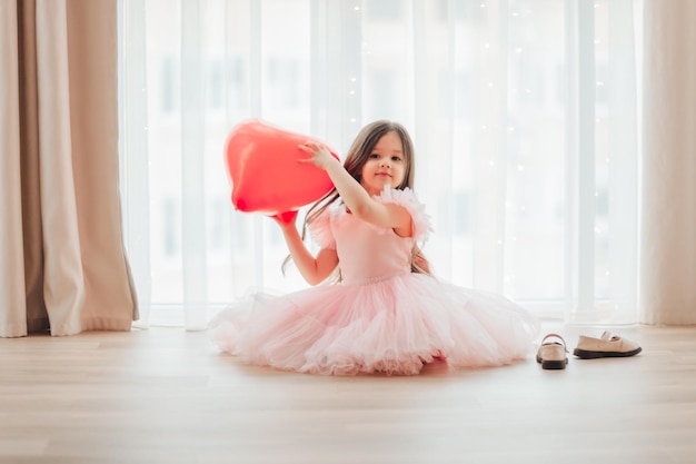 Valentine's day baby A little girl in a red dress holds a large ball in the shape of a heart