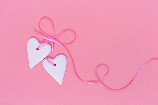 Valentine's Day background concept. Two Hearts hangs on ribbon on pink paper background with copy space. Top view.