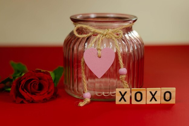 バレンタインデーの背景。ピンクの背景にガラスの花瓶に赤いバラ。
