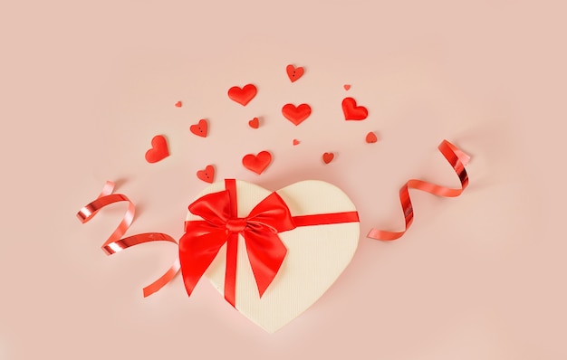ハートの形をしたバレンタインデーの背景ピンクの背景に赤いリボンが付いたハートの形のギフトボックス。愛の概念。