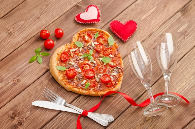 Valentine's day background with pizza heart and glasses of wine on a dark wooden background