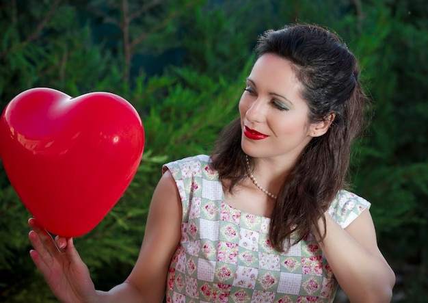 San valentino. bella donna sorridente con un regalo a forma di cuore nelle sue mani