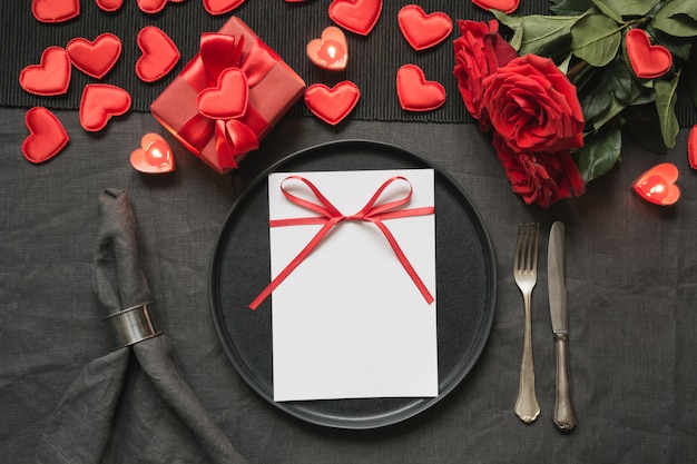 Valentine's day or birthday dinner. Elegance table setting with red rose on black linen tablecloth.