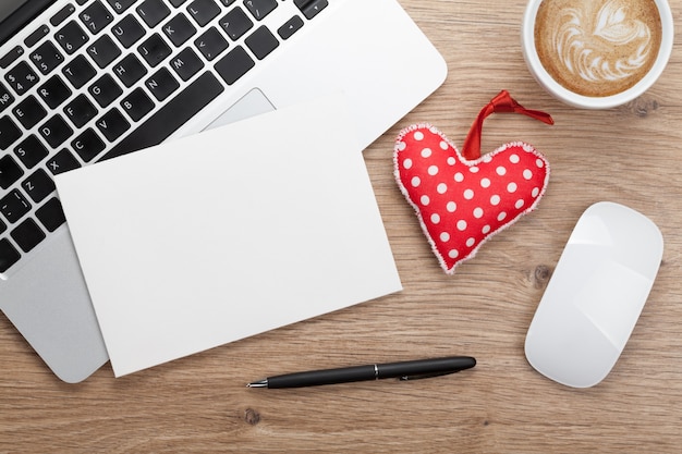 Valentine's day blank greeting card and toy heart over office workplace