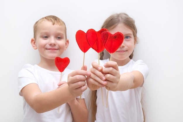 Valentine's day A boy and a girl are eating lollipops Red caramel in the shape of a heart