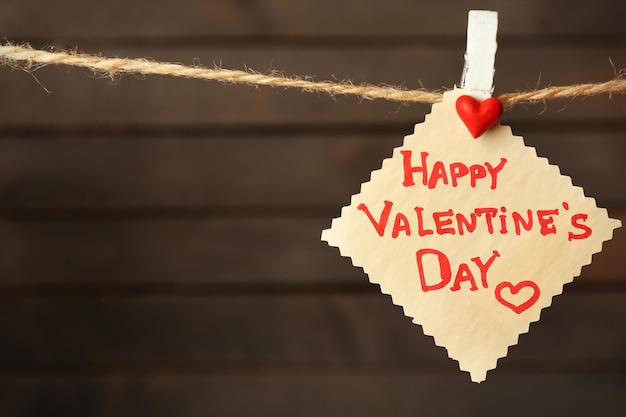 Valentine's Day card with hearts and words of love on wooden background