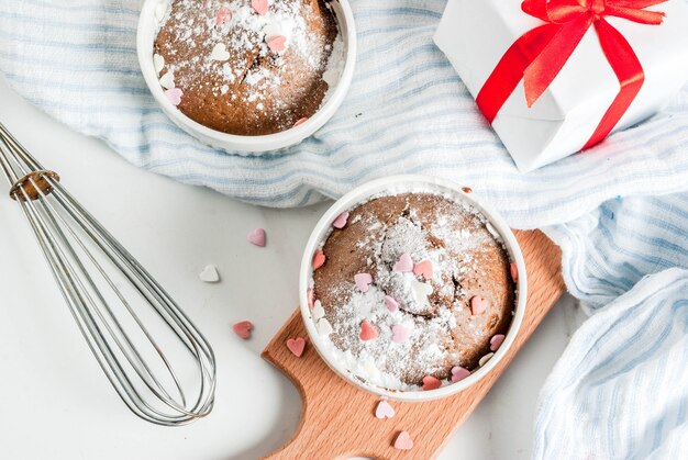 가루 설탕과 달콤한 심장 모양의 뿌리, 흰색 테이블, 상위 뷰 발렌타인 초콜릿 머그잔 케이크 또는 브라우니