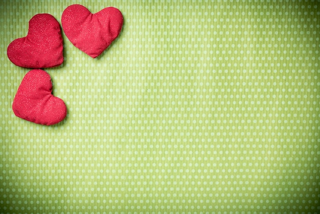 Фото День святого валентина. красочные вязаные сердечки на зеленом винтажном в горошек. красное сердце.