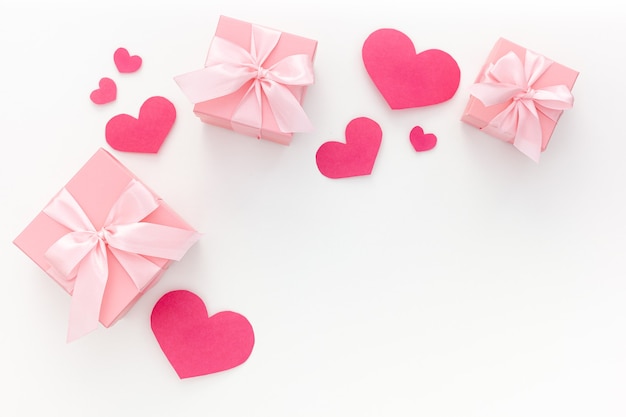 Valentine's day composition: three pink gift boxes with ribbon and paper hearts