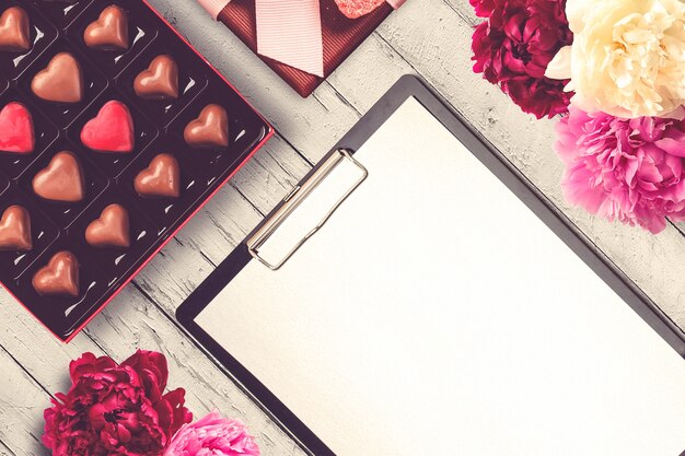 Valentine's Day composition with clipboard, flowers and chocolates