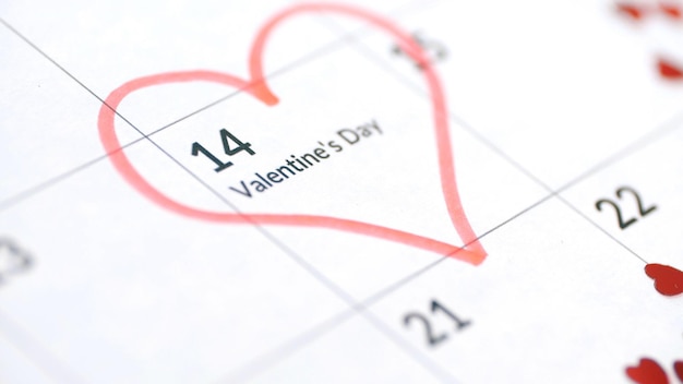 Valentine's day concept close up of calendar sheet with 14th February date marked by red heart shape