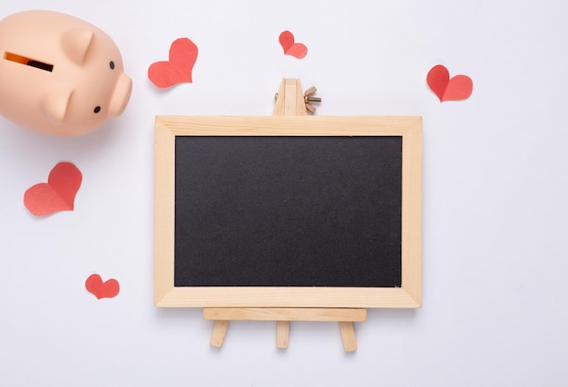 Valentine's day concept Piggy bank and hearts empty chalk board on a white background Copy space