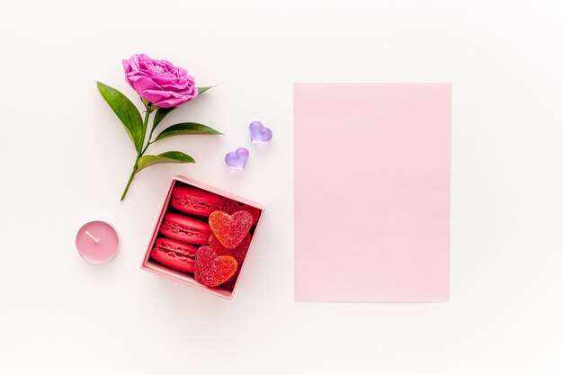 Valentine's day concept. Pink box with marmalade and macaroons and a beautiful rose on a pink table