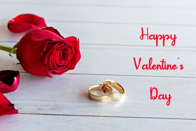 バレンタインデーのコンセプト、木製のテーブルにローズとゴールドの結婚指輪。