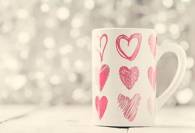 Concetto di san valentino con tazza con stampa a forma di cuore su bokeh bianco