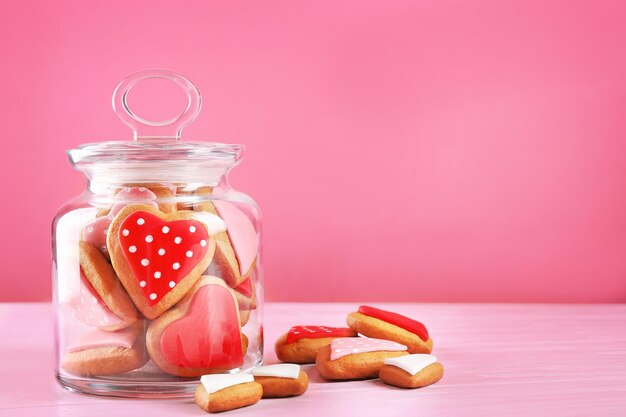 Valentine's day cookies in glass jar on pink background