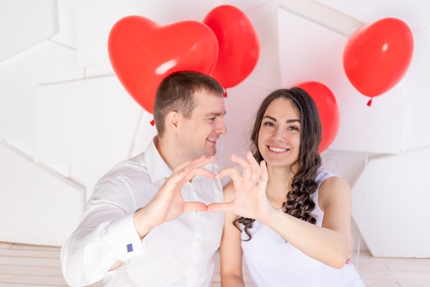 Valentine's day, a couple in love shows a heart from their hands and looks at each other with a loving look