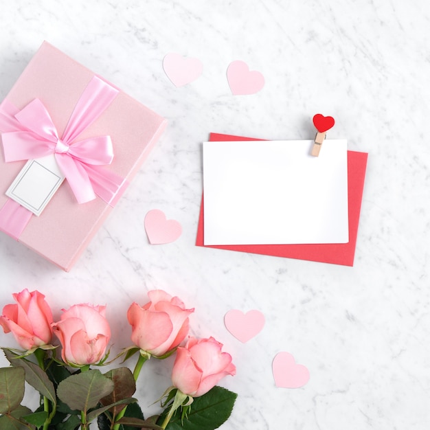 Valentine's Day design concept background with pink rose flower, gift box and card on marble white background