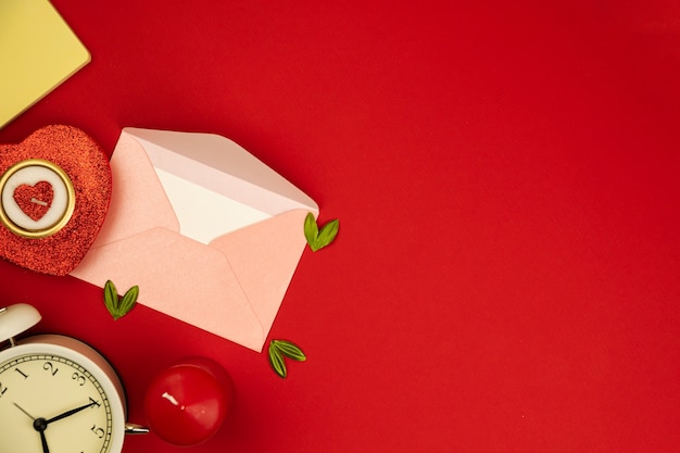 Composizione piatta di san valentino su sfondo rosso, busta di lettera d'amore, candela a forma di cuore e banner decorativo, copia spazio foto