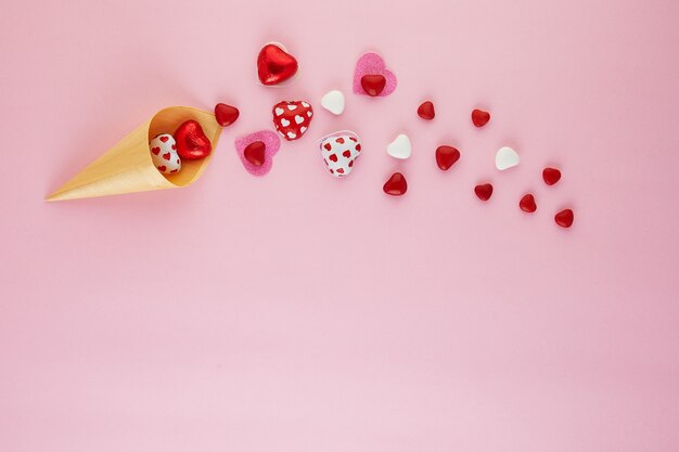 Il piatto di san valentino giaceva con cuori di caramelle che volavano da un cono gelato sul rosa