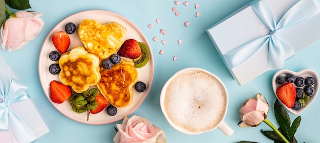 Photo valentine's day flat lay with heart shaped pancakes on a blue.