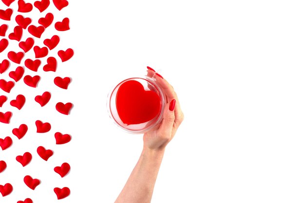사진 발렌타인 데이. 흰색 바탕에 빨간색 하트 프레임입니다. 손에 빨간 음료와 함께 심장 모양의 컵. 평면 위치, 평면도, 복사 공간.