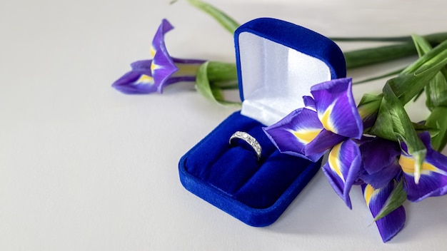 Valentine's day gift - bouquet of blue iris flowers and engagement ring in blue velvet box