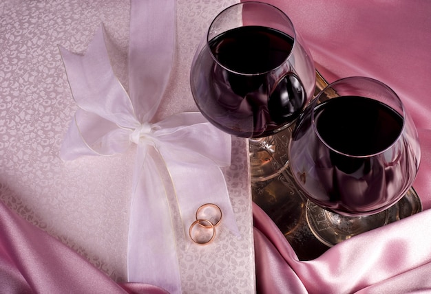 Valentine's Day. Gift box, flowers, glasses with wine on the pink color background