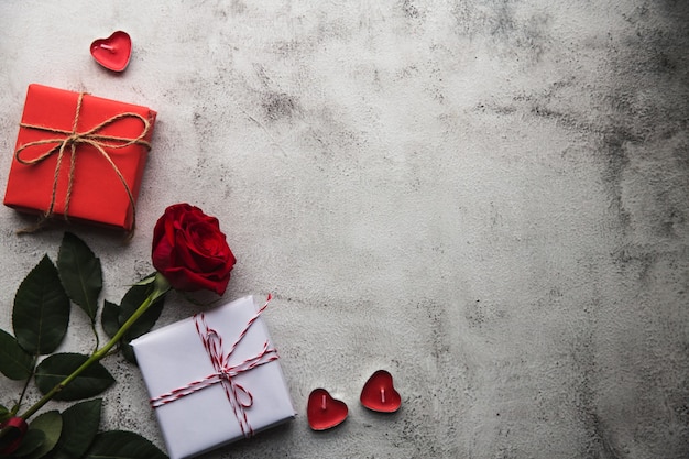 San valentino, confezione regalo di carta kraft con un nastro, rose e candele su sfondo grigio