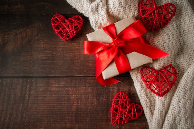 Valentine's Day gift in a box with a red ribbon on a brown background.