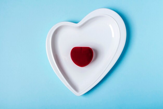 Valentine's day gift. Closed jewelry box on heart-shaped plate on pink. Marriage proposal, engagement concept.