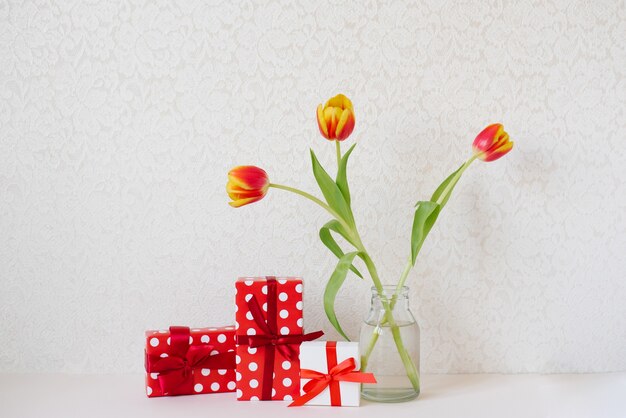 Valentine's Day greeting card. Gift red and white boxes with ribbons and bows and a bouquet of red and yellow tulips. Valentine's Day and Birthday