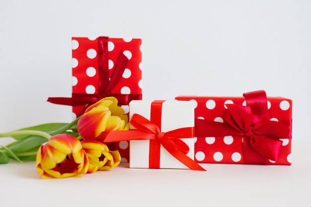 Valentine's Day greeting card. Gift red and white boxes with ribbons and bows and a bouquet of red and yellow tulips