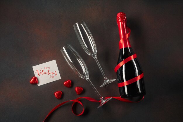 Valentine's day greeting card with champagne glasses and candy hearts on stone background. 