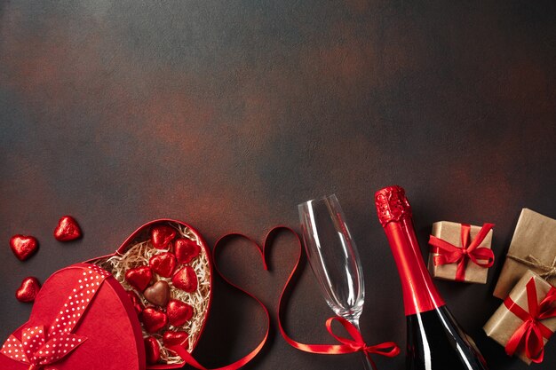 Valentine's day greeting card with champagne glasses and love gift box on stone background. 