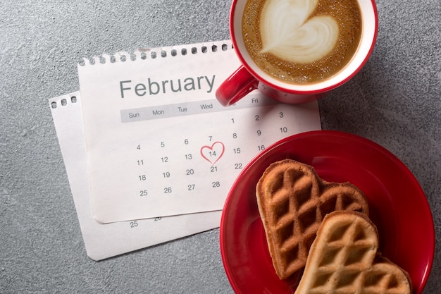 День Святого Валентина открытка с чашкой кофе и печенье в форме сердца на сером фоне.