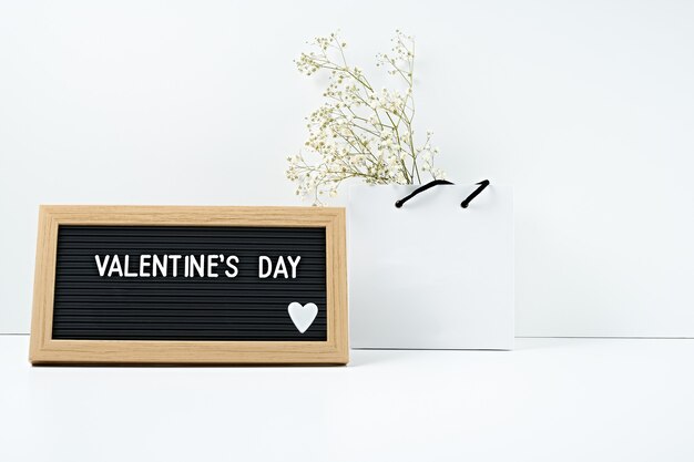 Valentine's day inscription in frame and gift box on white background.