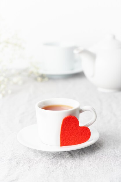 バレンタイン・デー。お茶と花を含む2人の朝の朝食。赤いフェルトの心