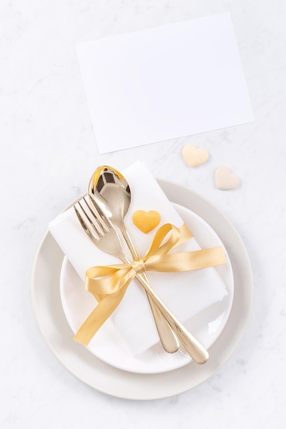 Valentine's Day Mother's Day holiday dating meal banquet design concept White plate and golden ribbon on marble background top view flat lay