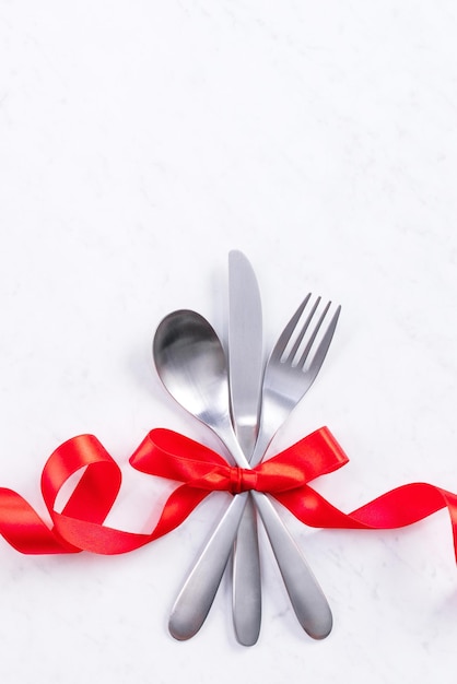 Valentine's Day Mother's Day holiday dating meal banquet design concept White plate and red ribbon on marble background top view flat lay