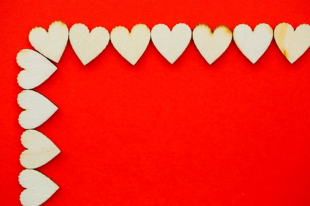 Valentine's day red background with wooden hearts and the word love. Place for inscriptions, advertising