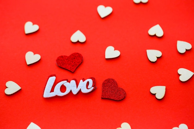 Valentine's day red background with wooden hearts and the word love. Place for inscriptions, advertising