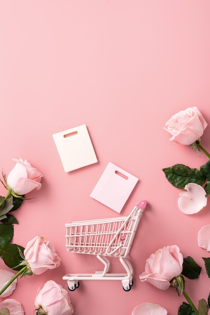 Valentine's Day shopping design concept background with pink rose flower and cart on pink table background