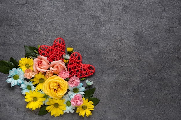 花と灰色の背景に赤いハートとバレンタインデーまたは結婚式のロマンチックなコンセプト。上面図、コピースペース。