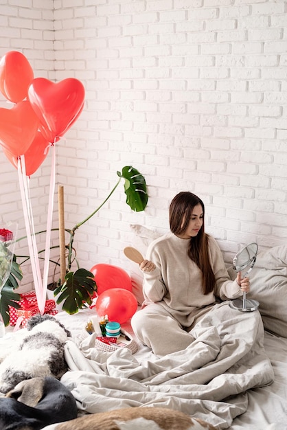 San valentino, festa della donna. giovane donna bruna che celebra il giorno di san valentino, seduta sul letto che compone