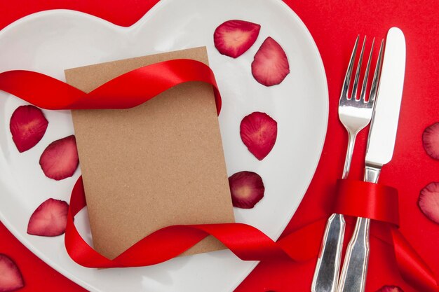 Foto concetto di cena di san valentino piatto a forma di cuore con una scheda vuota