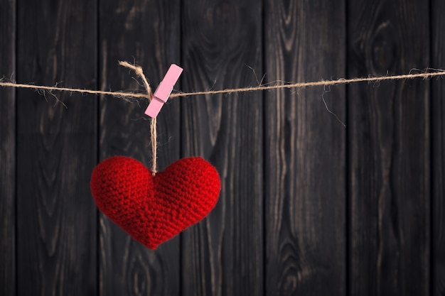 Valentine's Red heart on rope on wooden background