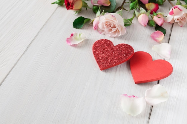 valentine with pink rose flowers petals and handmade wooden hearts on white rustic wood