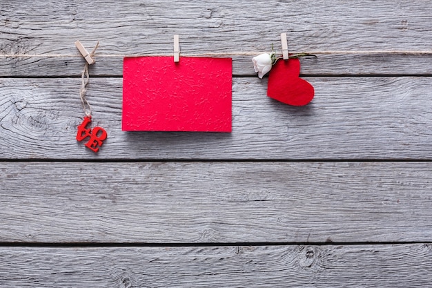 Valentine with red paper heart and empty greeting card on clothespins on rustic wood planks