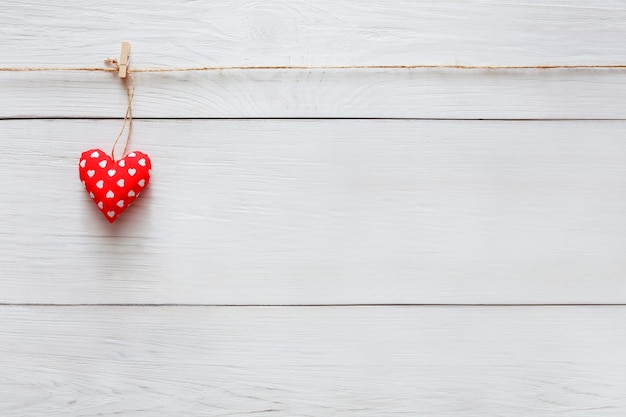 Valentine with single sewed pillow diy handmade heart on red clothespins at rustic white wood planks